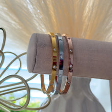Charger l'image dans la galerie, A set of stainless steel bangle bracelets with 18K gold, silver, and rose gold colors, adorned with crystal clovers, displayed on a stand.