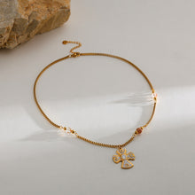 Carregar imagem no visualizador da galeria, Gold necklace with a pendant on a light gray surface